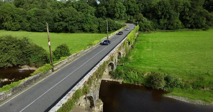 Three cars drive over the old stone bridge 4k