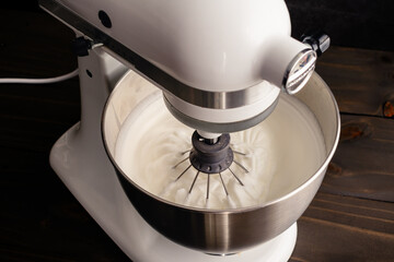 Stand Mixer with a Whisk Attachment in Beaten Egg Whites: Electric mixer in the down position with...