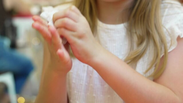 Teenage girl wipes her hands with a damp cloth after eating in a cafe. 