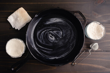 Cast-Iron Skillet Greased with Vegetable Shortening: Hydrogenated vegetable fat rubbed inside a frying pan with a folded paper towel - obrazy, fototapety, plakaty