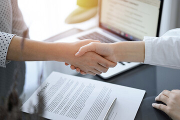 Business people shaking hands above contract papers just signed on the white table, closeup. Lawyers at meeting. Teamwork, partnership, success concept