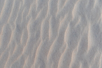 Blurred image of fine, delicate coastal sand on beach under thin layer of transparent sea water