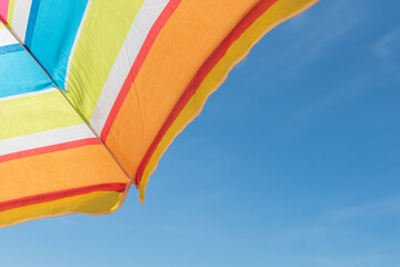 Multicolored sun umbrella against blue sky in sunlight