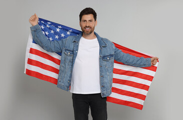 4th of July - Independence Day of USA. Happy man with American flag on grey background