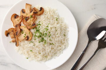 Delicious rice with parsley and mushrooms served on white marble table, flat lay