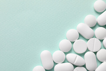 White pills on mint background, flat lay. Space for text