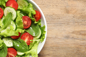 Delicious vegetable salad on wooden table, top view. Space for text