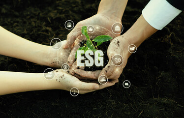 Businessman and little kid growing or nurturing plant together on fertile soil with eco friendly...