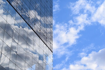 Fototapeta na wymiar Reflection of the blue sky on a glass facade of a high rise skyscraper building