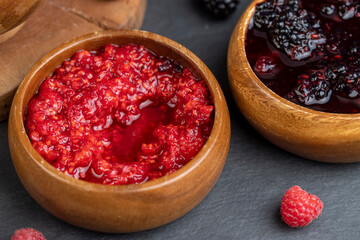 crumpled juicy red raspberries in a wooden bowl