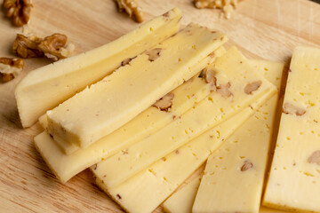 Sliced piece of milk cheese with walnuts