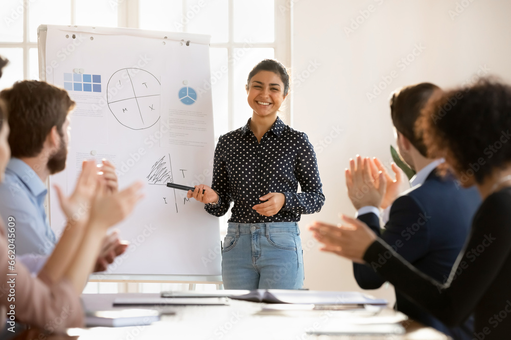 Wall mural Business audience applauding happy pretty young Indian presenter, coach, expressing acknowledgment, recognition for educating training, marketing seminar, thanking for meeting