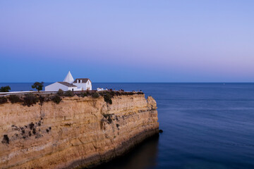 View to the big cliff and the Chapel of Our Lady of the Rock (Igreja de Nossa Senhora da Rocha). Dreamy tranquil sunset scenery.  Porches, Algarve, Portugal