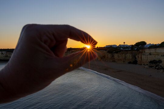 Hand catching the sun on a sunset on a beach of the Algarve, Portugal.
