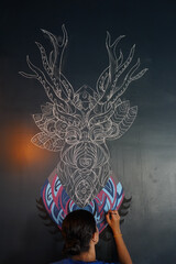 Woman drawing a picture on the wall with a brush. Beautiful model woman making artistic drawing on the wall