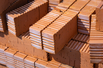 Rows of red bricks. The group or the pile of new clay red orange bricks close-up on the outside warehouse or the construction site. The selected focus