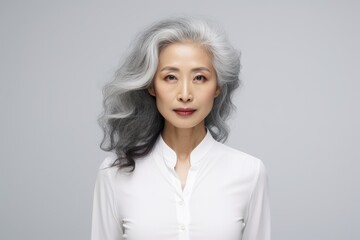 Stylish confident adult 50 years old asian woman  looking at camera on light background.  Middle-aged  women with silver gray short hair.  Beauty, skin care, spa concept. Plastic surgery