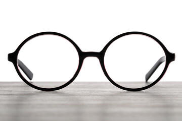 Stylish glasses with black frame on wooden table against white background - obrazy, fototapety, plakaty