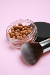 Face powder balls and brush on pink background