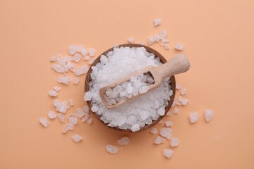 Bowl and scoop with sea salt on beige background, top view