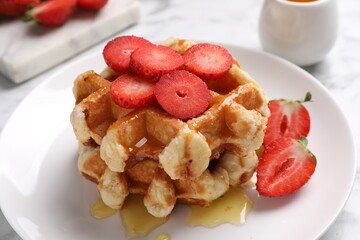 Delicious Belgian waffles with strawberries and honey on table, closeup
