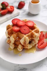 Delicious Belgian waffles with strawberries and honey on white marble table, closeup