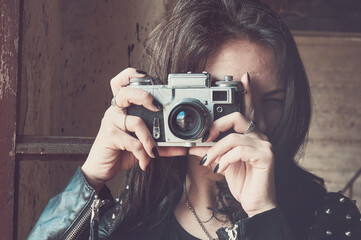 Close-up portrait of a photographer. A brunette girl takes photographs with a film camera produced...