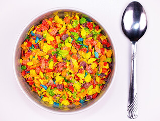 Photograph of a breakfast bowl featuring a colorful, crispy cereal and a metal spoon. 