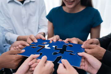 Diverse corporate officer workers collaborate in office, connecting puzzle pieces to represent...