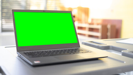 Open laptop with a blurry background and a green screen.