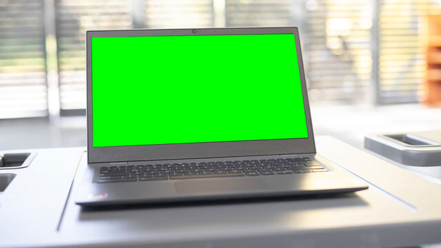 Open laptop with a blurry background and a green screen.