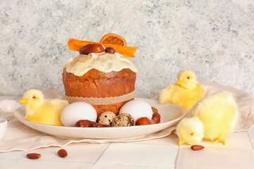 Easter cake with chicken figures and eggs on white tile table near light grunge wall