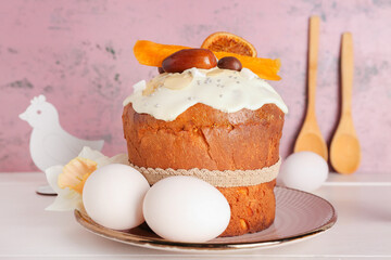 Easter cake with chicken figures and eggs on white wooden table near pink grunge wall
