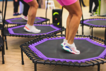 Trampoline fitness jumping training, group of young fit women in sportswear jump on trampolines,...
