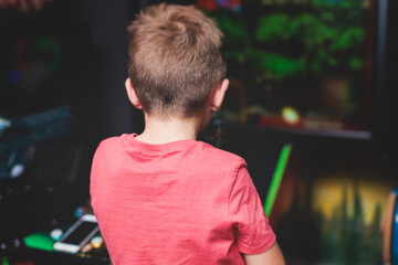 Kids play slot machine at amusement theme park, children play arcade gaming machine, racing and...