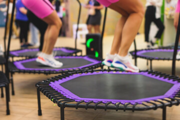 Trampoline fitness jumping training, group of young fit women in sportswear jump on trampolines, girls training with coach instructor, exercising on rebounder at the gym, mini trampoline workout