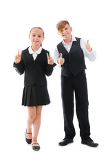 Little classmates in stylish uniform with backpacks showing thumbs-up gesture on white background