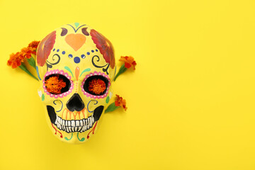 Painted human skull for Mexico's Day of the Dead (El Dia de Muertos) with flowers on yellow...
