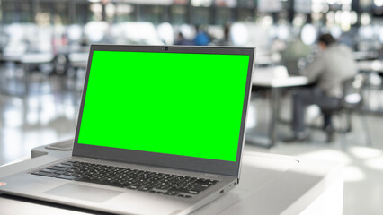 Open laptop with a blurry background and a green screen. - obrazy, fototapety, plakaty