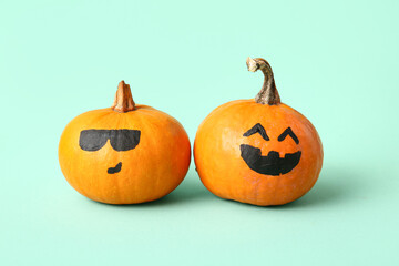 Funny Halloween pumpkins with drawn faces on turquoise background