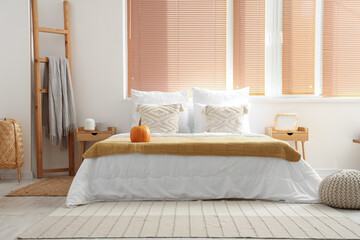Interior of light bedroom with pumpkin on bed