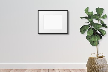 Horizontal Black Picture Frame Mockup hanging on a White Wall with a Potted Fiddle Leaf Fig Plant...