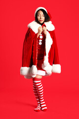 Young Asian woman in Santa costume on red background