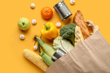 Paper shopping bag with different fresh products on yellow background