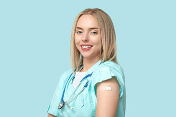 Female doctor with medical patch on arm against blue background. Vaccination concept
