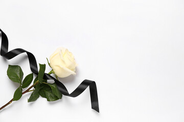 Black mourning ribbon and rose on white background