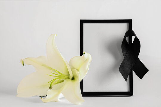 Photo frame with black ribbon and lily flower on white background