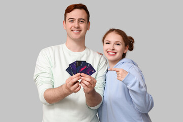 Young couple pointing at credit cards on grey background