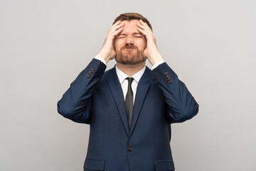 Man touching head, frown disappointed sickly emotional face with closed eyes on grey background. Businessman having problems troubles in business. Losing money, burnout, desperation, failure concept.