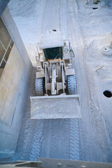 Wheel loader transports calx products in bucket at factory